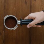 Barista holding a portafilter of spent coffee grounds, the waste a coffee catcher keeps out of cafe drains